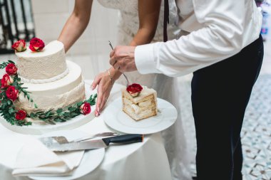 Düğün töreni. Gelin ve damat ilk davalarını birlikte yapıyorlar. Çiçekle süslenmiş güzel düğün pastasını kesiyorlar.