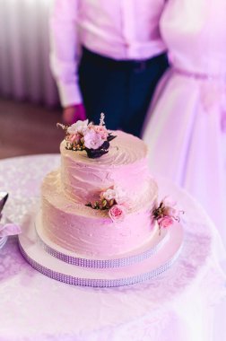 Düğün töreni. Gelin ve damat ilk davalarını birlikte yapıyorlar. Çiçekle süslenmiş güzel düğün pastasını kesiyorlar.