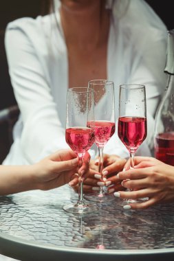 İnsanlar pembe şampanyayla el ele tutuşuyorlar. parti.