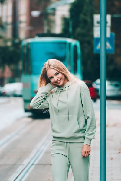 一位穿着浅绿色运动服的漂亮金发女子在街上摆姿势 迷人的女模特在户外摆姿势 健身女士 — 图库照片