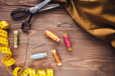 Dikiş Araçları ve aksesuarları kahverengi ahşap zemin, üstten görünüm, kopya alanı tasarlamak çerçeve