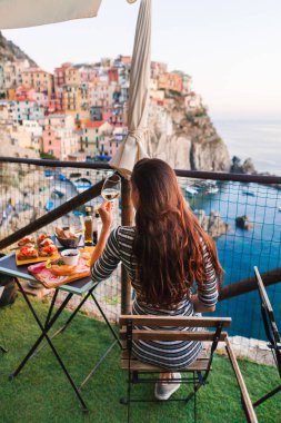 Kadın, iki gün batımında romantik akşam yemeğinde. Beyaz şarap ve lezzetli İtalyan snack: taze bruschettes ve et Manarola, İtalya için muhteşem manzaralı açık Cafe gemide
