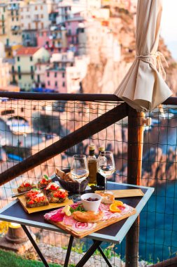 İki gün batımında romantik yemek. Beyaz şarap ve lezzetli İtalyan snack: taze bruschettes ve et Manarola, İtalya için muhteşem manzaralı açık Cafe gemide