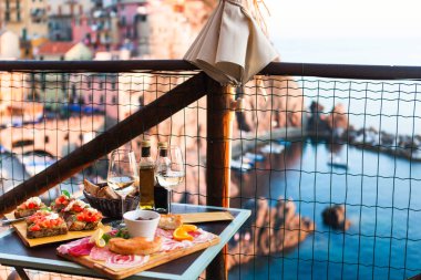 İki gün batımında romantik yemek. Beyaz şarap ve lezzetli İtalyan snack: taze bruschettes ve et Manarola, İtalya için muhteşem manzaralı açık Cafe gemide