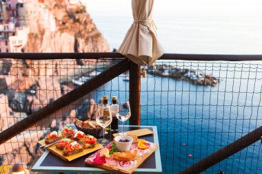 İki gün batımında romantik yemek. Beyaz şarap ve lezzetli İtalyan snack: taze bruschettes ve et Manarola, İtalya için muhteşem manzaralı açık Cafe gemide