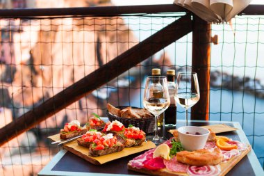 İki gün batımında romantik yemek. Beyaz şarap ve lezzetli İtalyan snack: taze bruschettes ve et Manarola, İtalya için muhteşem manzaralı açık Cafe gemide