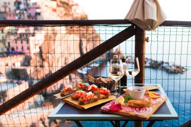 İki gün batımında romantik yemek. Beyaz şarap ve lezzetli İtalyan snack: taze bruschettes ve et Manarola, İtalya için muhteşem manzaralı açık Cafe gemide