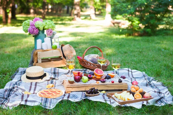 绿色草地上的白葡萄酒和夏日水果的野餐背景 — 图库照片