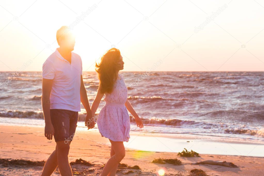 Happy young family relaxing on beach at sunset. Family traveling romantic concept