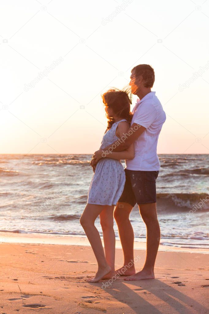 Happy young family relaxing on beach at sunset. Family traveling romantic concept