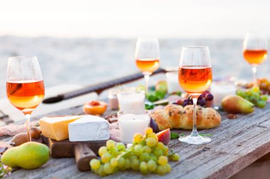 Boho tarzı gün batımında sahilde piknik. Romantik bir akşam yemeği, arkadaş parti, yaz aylarında, yiyecek ve içecek anlayışı