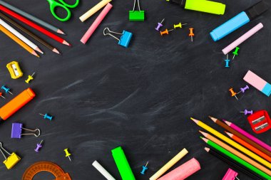 Back To School concept. School supplies on blackboard background, accessories for the schoolroom - pencils, notebooks, scissors, chalk, markers.  Copy space top view