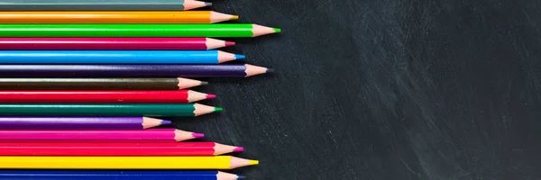 Back to School concept. Colorful pencils on blackboard background. Close up, flat lay, copy space, top view, long banner, long banner