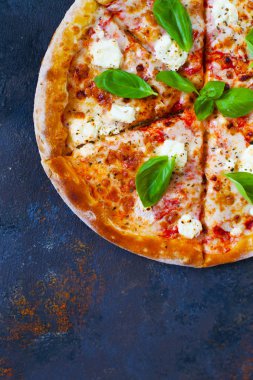 Ev yapımı sıcak pizza domates, mozzarella ve fesleğen ile. Karanlık taş tablo kopya alanı ile üstten görünüm.