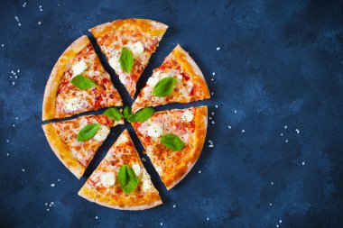 Ev yapımı sıcak pizza domates, mozzarella ve fesleğen ile. Karanlık taş tablo kopya alanı ile üstten görünüm.