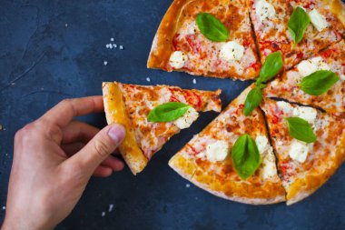 Ev yapımı sıcak pizza domates, mozzarella ve fesleğen ile. Karanlık taş tablo kopya alanı ile üstten görünüm.