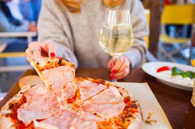 İtalyan yemek yemek. Pizza domates jambon ve mozzarella ve içki beyaz şarap yaz açık hava restoranı ile yemek kadın