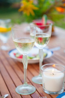 İki bardak beyaz şarap. Aile açık yemek bahçede yaz gün batımında. Piknik yiyecek ve içecek konsepti