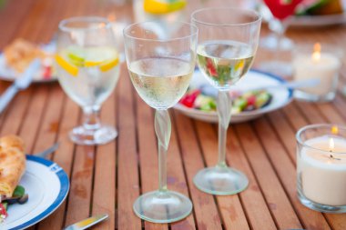 İki bardak beyaz şarap. Aile açık yemek bahçede yaz gün batımında. Piknik yiyecek ve içecek konsepti