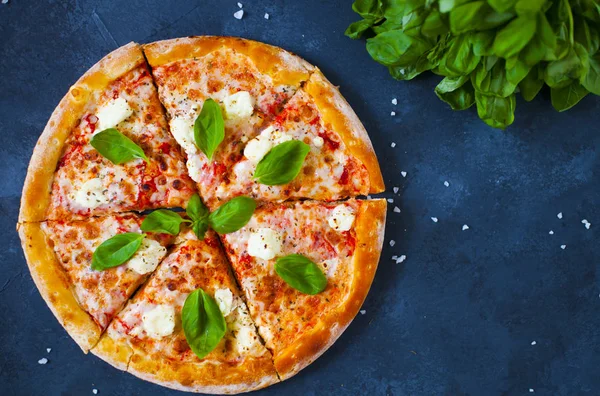 Ev yapımı sıcak pizza domates, mozzarella ve fesleğen ile. Karanlık taş tablo kopya alanı ile üstten görünüm.