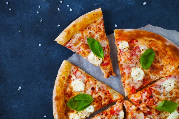 Ev yapımı sıcak pizza domates, mozzarella ve fesleğen ile. Karanlık taş tablo kopya alanı ile üstten görünüm.