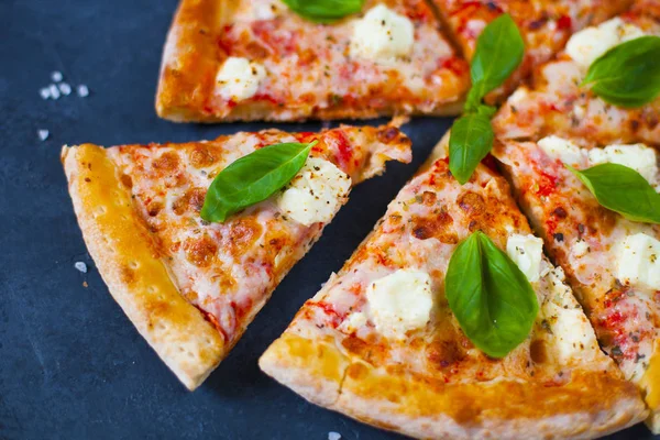 Ev yapımı sıcak pizza domates, mozzarella ve fesleğen ile. Karanlık taş tablo kopya alanı ile üstten görünüm.