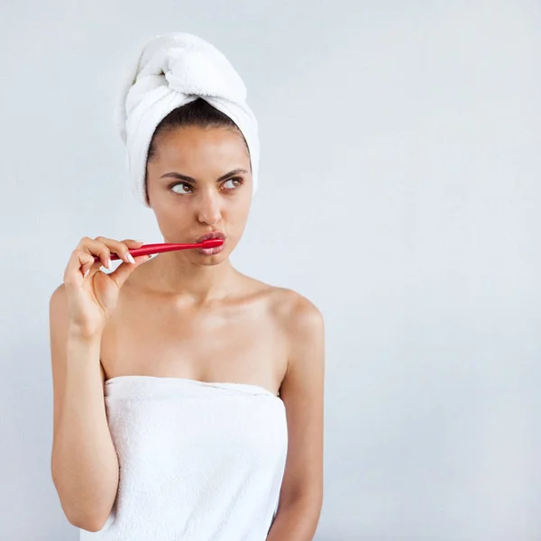 Smiling happy young woman with healthy teeth holding a tooth brush white background. Clean beauty and healthy concept