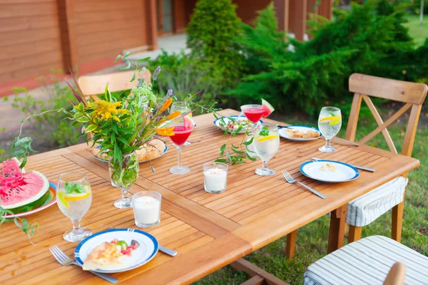 Family outdoor dinner in the garden in summertime at sunset. Picnic food and drink concept