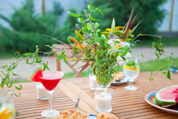 Family outdoor dinner in the garden in summertime at sunset. Picnic food and drink concept