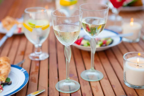 İki bardak beyaz şarap. Aile açık yemek bahçede yaz gün batımında. Piknik yiyecek ve içecek konsepti