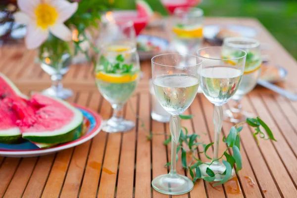 Two glasses of white wine. Family outdoor dinner in the garden in summertime at sunset. Picnic food and drink concept