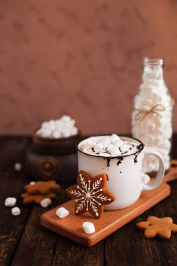 Bir fincan sıcak çikolata veya kakao ile Noel kurabiyeleri ve koyu ahşap arka plan üzerinde marsmallow