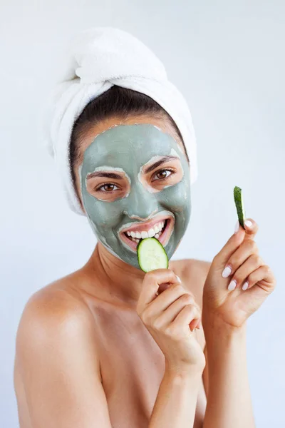 Young beautiful woman in face mask of therapeutic blue mud. Spa treatment, self care and healthy skin. Copy space, white background