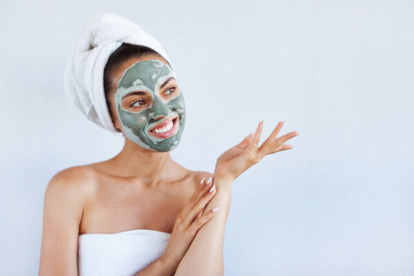 Young beautiful woman in face mask of therapeutic blue mud. Spa treatment, self care and healthy skin. Copy space, white background