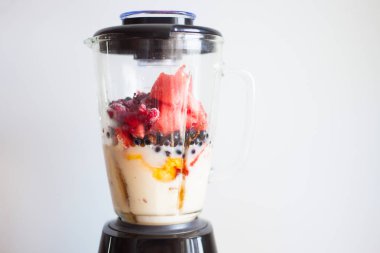 A blender filled with fresh whole fruits for making a smoothie o clipart