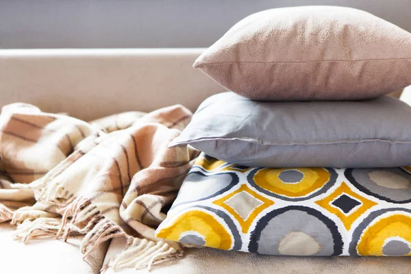 Bej kanepeüzerinde yastıklar ve ekose kopyalama alanı ile yakın. S