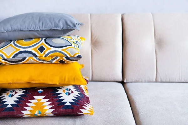 Multi-colored pillows on a beige fabric sofa, the concept of hom