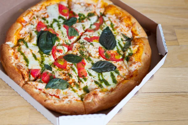 Warme smakelijke Italiaanse pizza met groenten in doos op houten blauw — Stockfoto