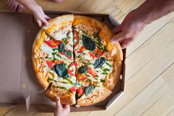 Obiad w grupie rodzinnej. Ręce biorące kromki pizzy z pudełkiem. Frie — Zdjęcie stockowe