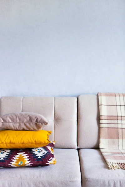Подушки и клетка на бежевом диване закрываются копировальным пространством. S Лицензионные Стоковые Изображения