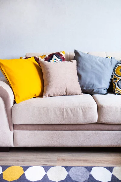 Многоцветные подушки на бежевом диване из ткани, концепция домашнего очага Лицензионные Стоковые Фото