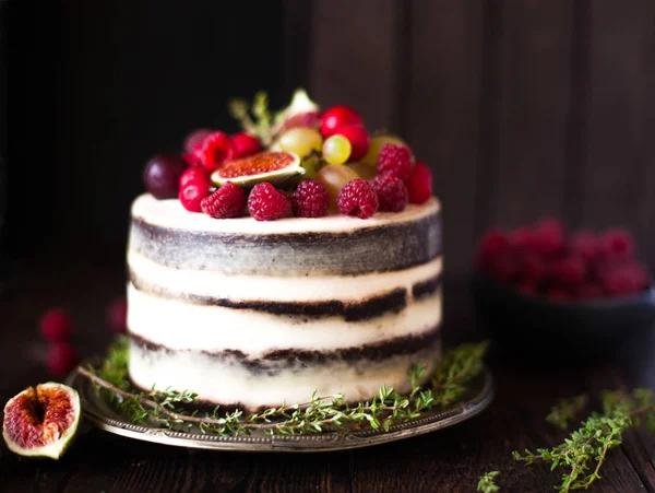 Delicioso pastel de chocolate con higos y bayas en un respaldo rústico Imagen De Stock