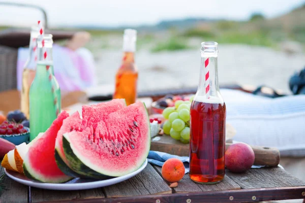 Picnic en la playa al atardecer al estilo boho, comida y bebida Imágenes de stock libres de derechos