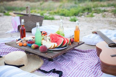 Gün batımında sahilde piknik tarzı boho, yiyecek ve içecek 