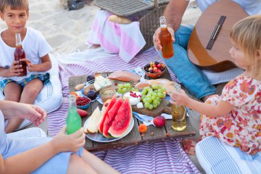 Gün batımında sahilde piknik tarzı boho, yiyecek ve içecek 