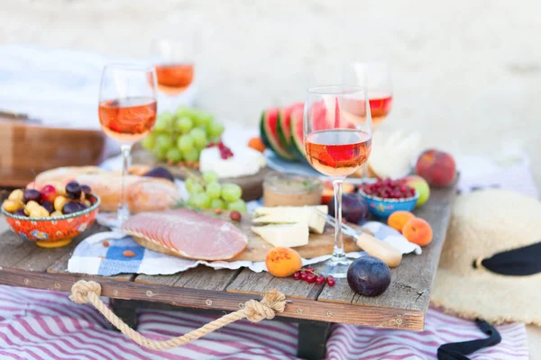 Picnic sulla spiaggia al tramonto in stile boho, cibo e dri — Foto Stock