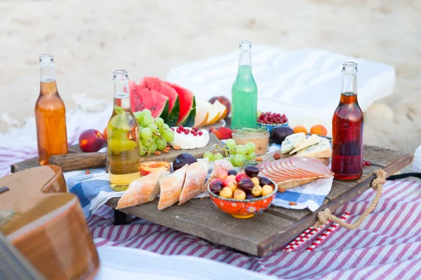 Piquenique na praia ao pôr do sol no estilo boho, comida e bebida — Fotografia de Stock