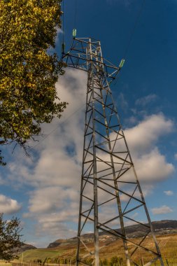 Bulutlu gökyüzü arka plan bir çayır tepe üzerinde elektrik Kulesi.