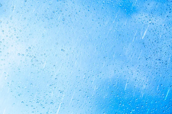 Капли дождя на фоне голубого стекла — стоковое фото