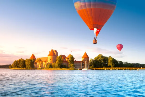 島とトラカイの飛行の気球に赤れんが造りの城のある風景します。 — ストック写真